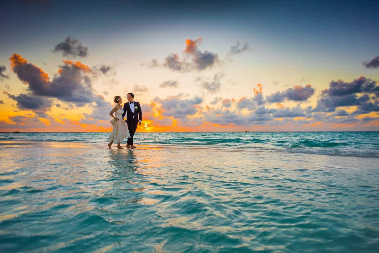 about-us A young couple enjoying a romantic beach wedding during a vibrant sunset.