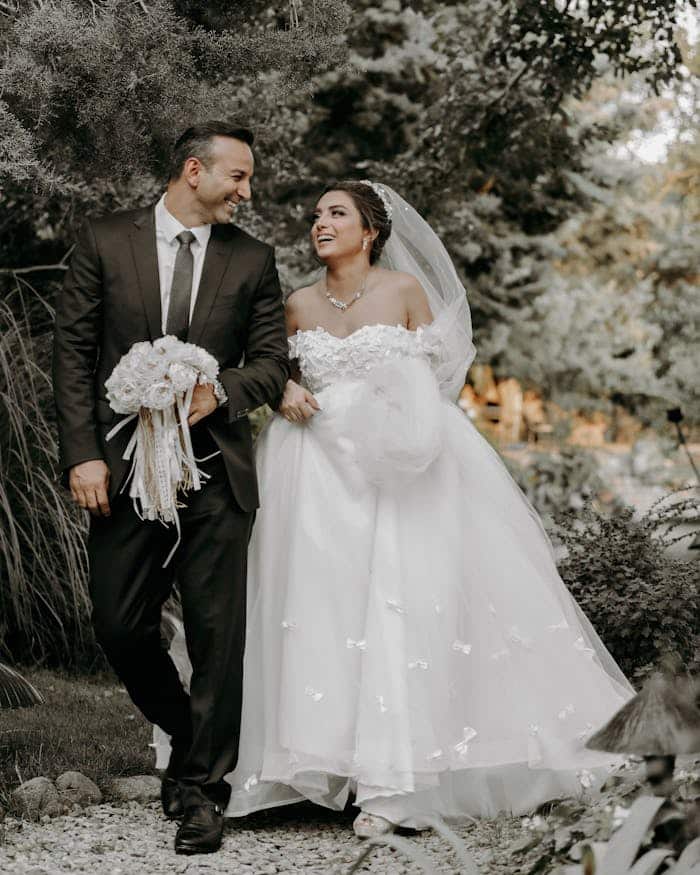 our-story Happy bride and groom walking together outdoors on their wedding day.