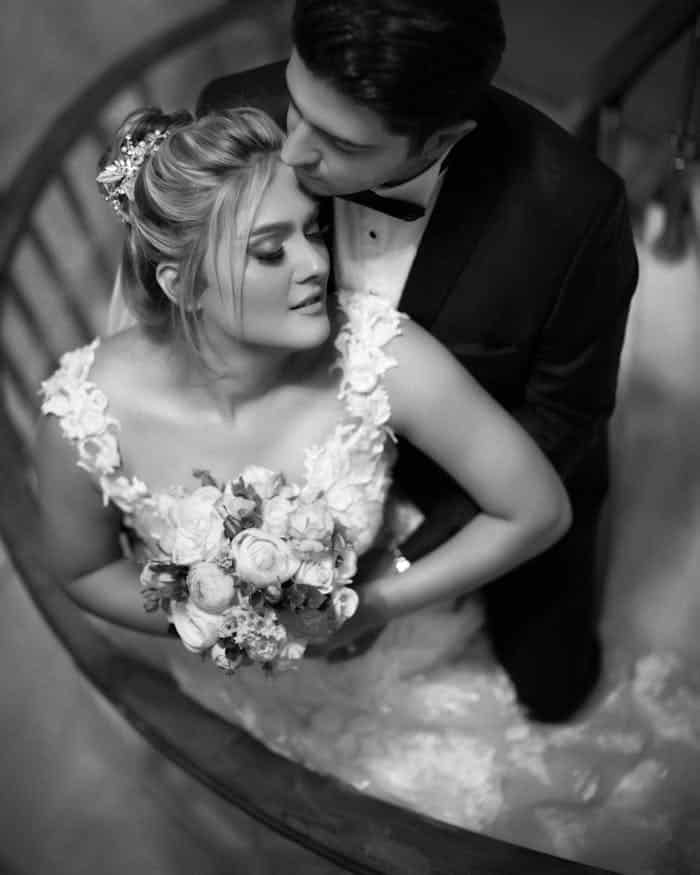 who-we-are Elegant black and white photo of a bride and groom embracing on a staircase.
