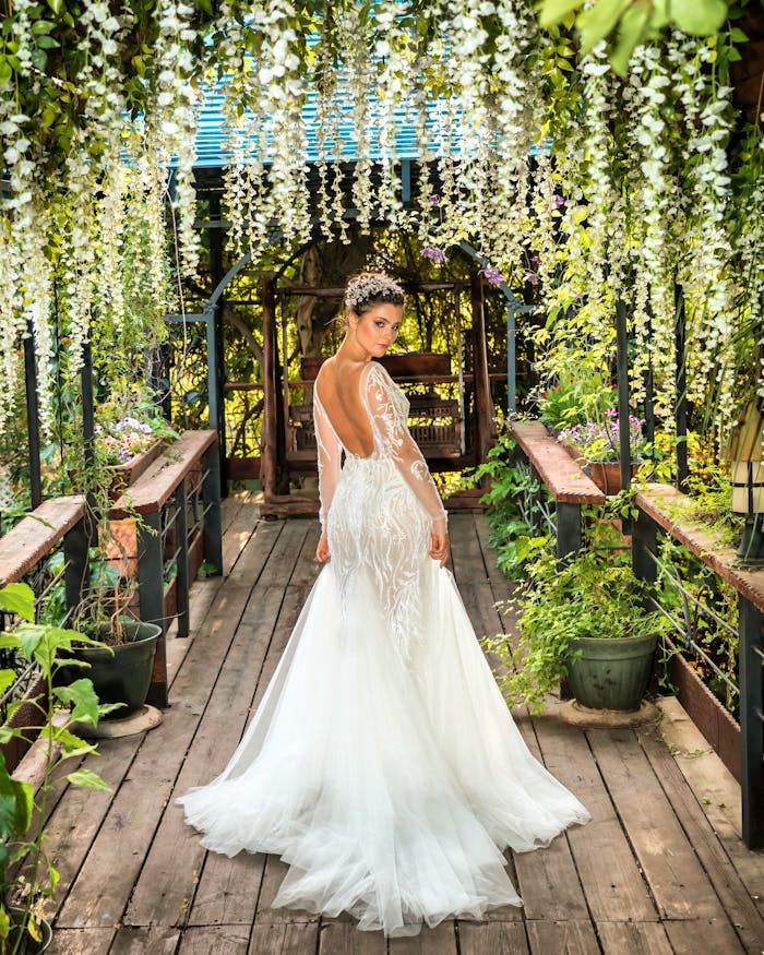 about-us Bride in a stunning white bridal gown posing in a lush garden archway